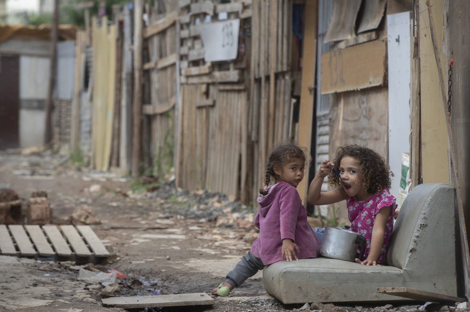 A girl eats from a pot as she eyes the camera in the Penha Brasil favela where families have started relocating during the coronavirus pandemic in Sao Paulo, Brazil, May 15, 2021. (AP File Photo)