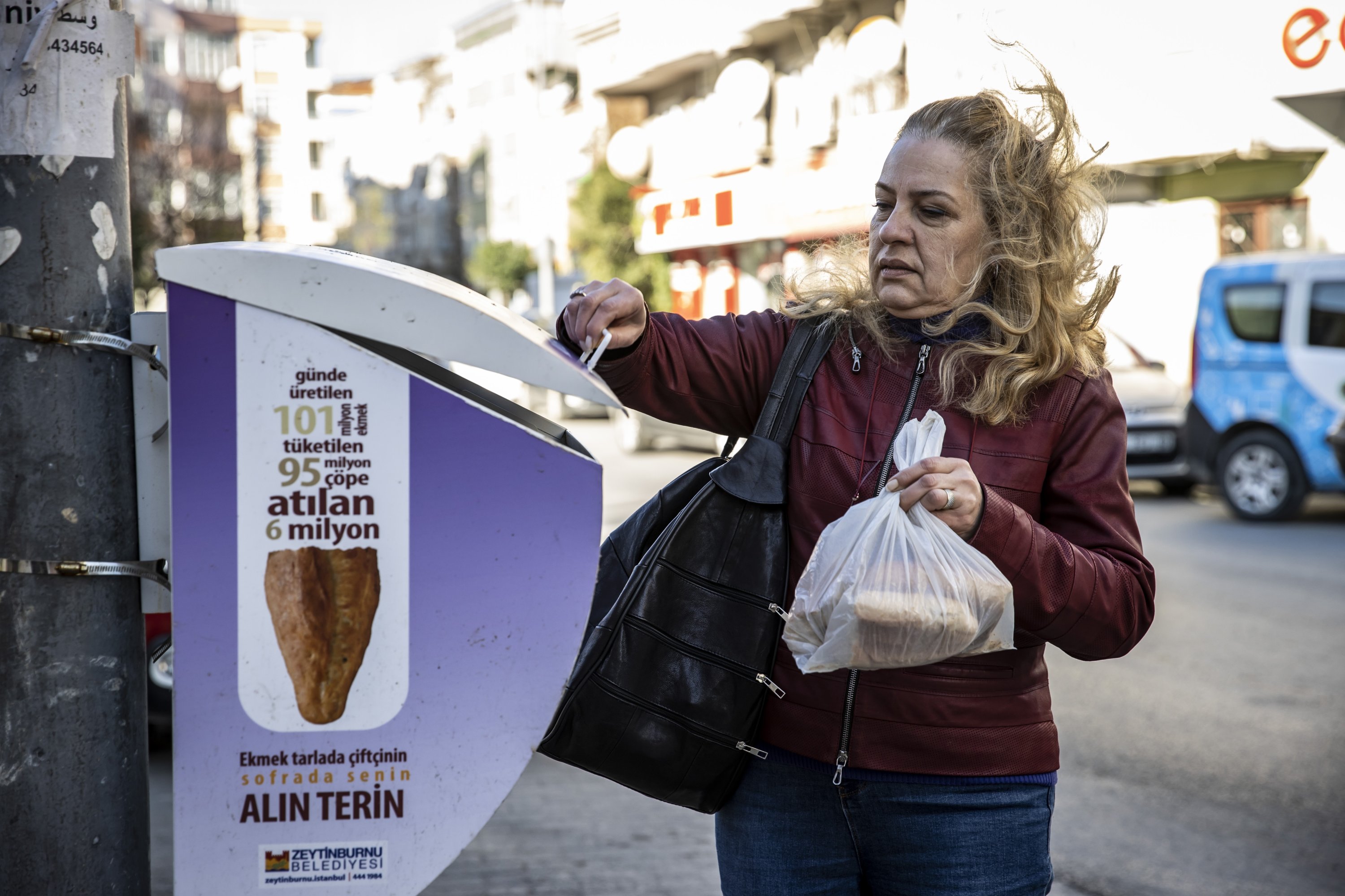 A woman puts leftover bread into a bread dumpster, in Zeytinburnu district, Istanbul, Turkey, Dec. 13, 2021. (AA Photo)