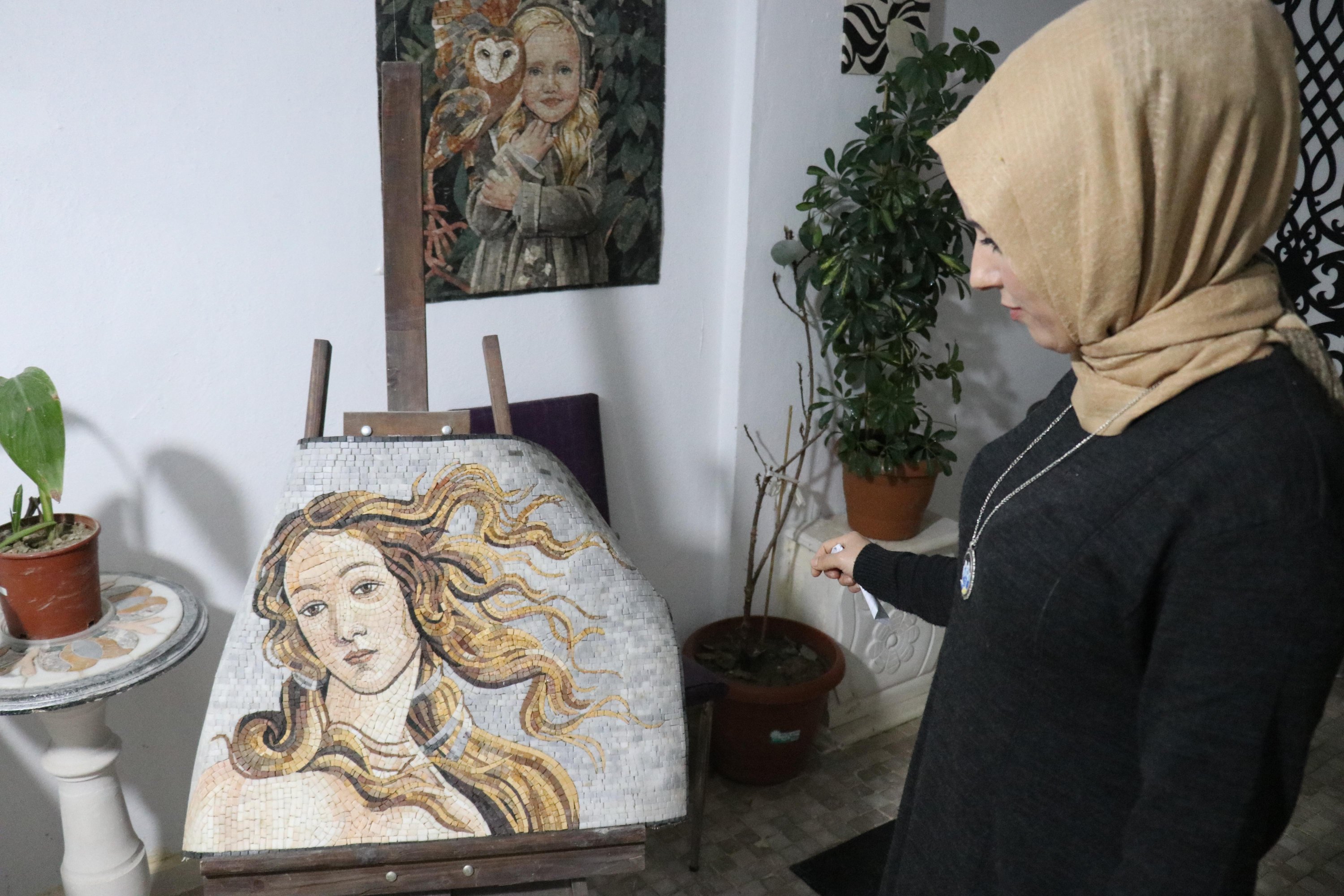 Zemzem Gök poses with a mosaic she prepared with Fatma Dendüş in their workshop, Hatay, southern Turkey, Dec. 12, 2021. (AA)