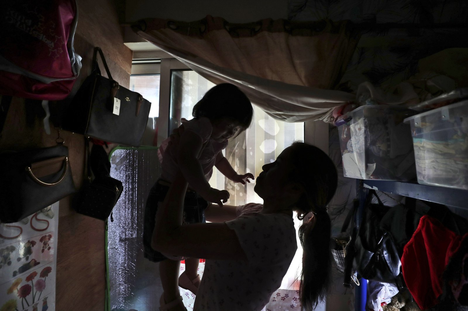 Maya, 36, plays with her 1-year-old undocumented daughter in a dank, overstuffed section of an apartment, subdivided by hinged partitions, that she shares with eight other women, in Dubai, United Arab Emirates, Nov. 24, 2021. (AP Photo)