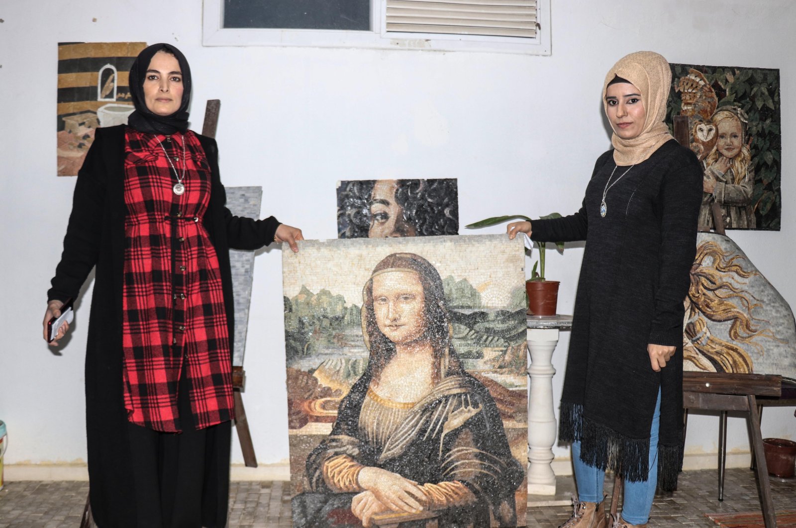 Zemzem Gök (R) and Fatma Dendüş pose with a mosaic they created together in their workshop, Hatay, southern Turkey, Dec. 12, 2021. (AA)