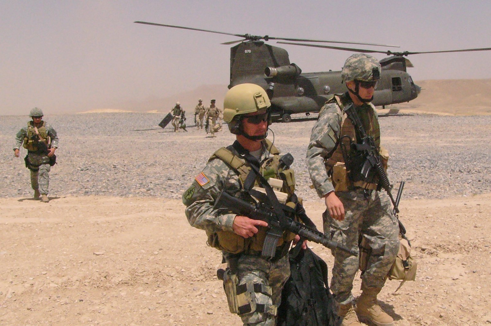 U.S. soldiers, with a Chinook helicopter in the background, return to their base after attending a local tribal council in Zabul province, south of Afghanistan, June 30, 2005. (Reuters File Photo)