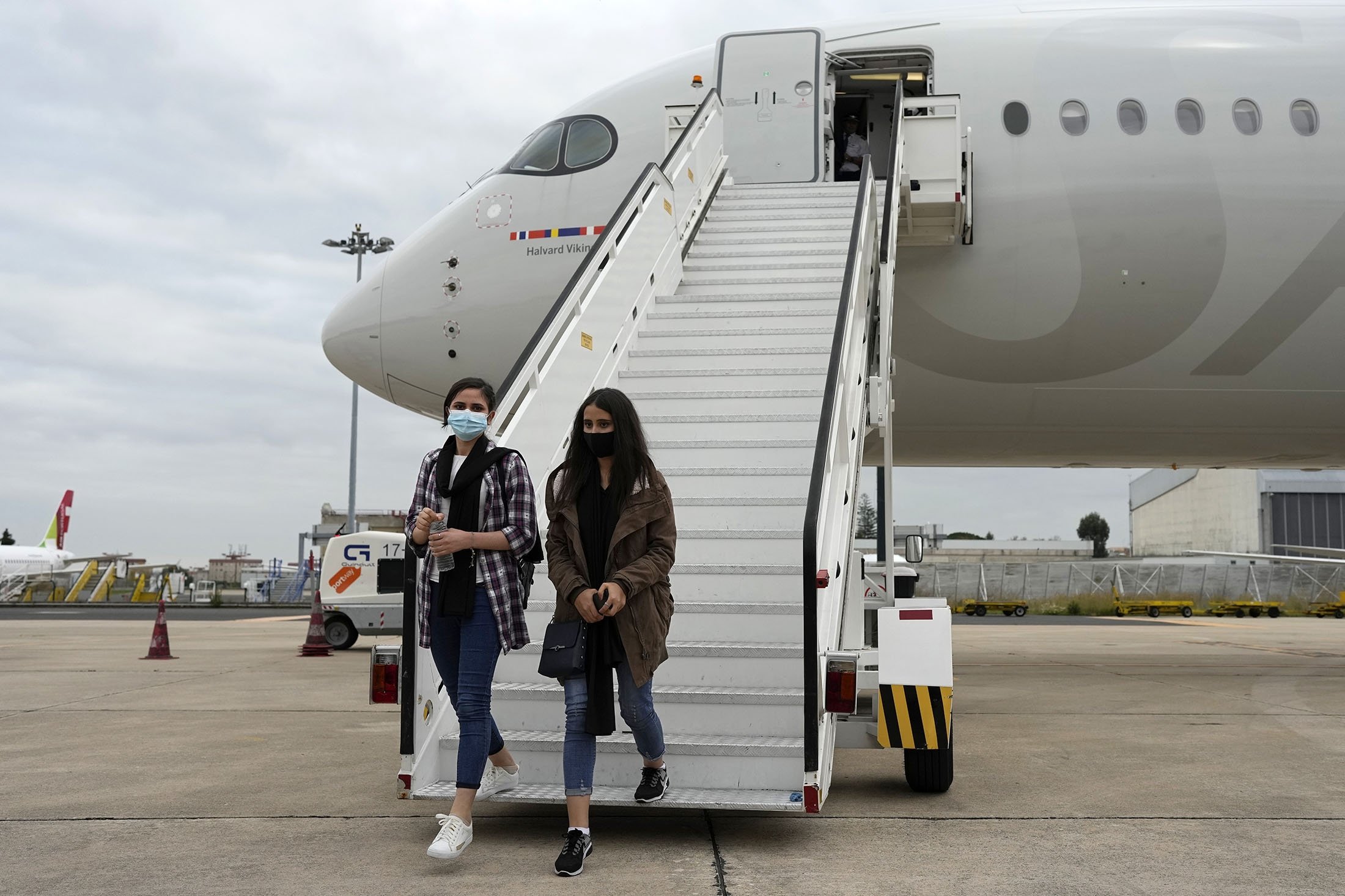Afghan musicians Shogofa Safi (L) and Marzia Anwari disembark from an airplane at a military airport, in Lisbon, Portugal, Dec. 13, 2021. (AP Photo)