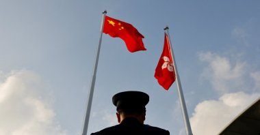 A police officer stands guard below China and Hong Kong flags during a flag raising ceremony, a week ahead of the Legislative Council election in Hong Kong, Dec. 12, 2021. (Reuters Photo)