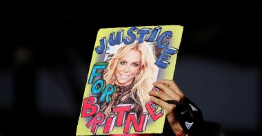 A supporter of singer Britney Spears holds up a picture of the pop star with the words "Justice for Britney" during celebrations of the termination of her conservatorship, outside the Stanley Mosk Courthouse in Los Angeles, California, U.S. Nov. 12, 2021. (REUTERS)