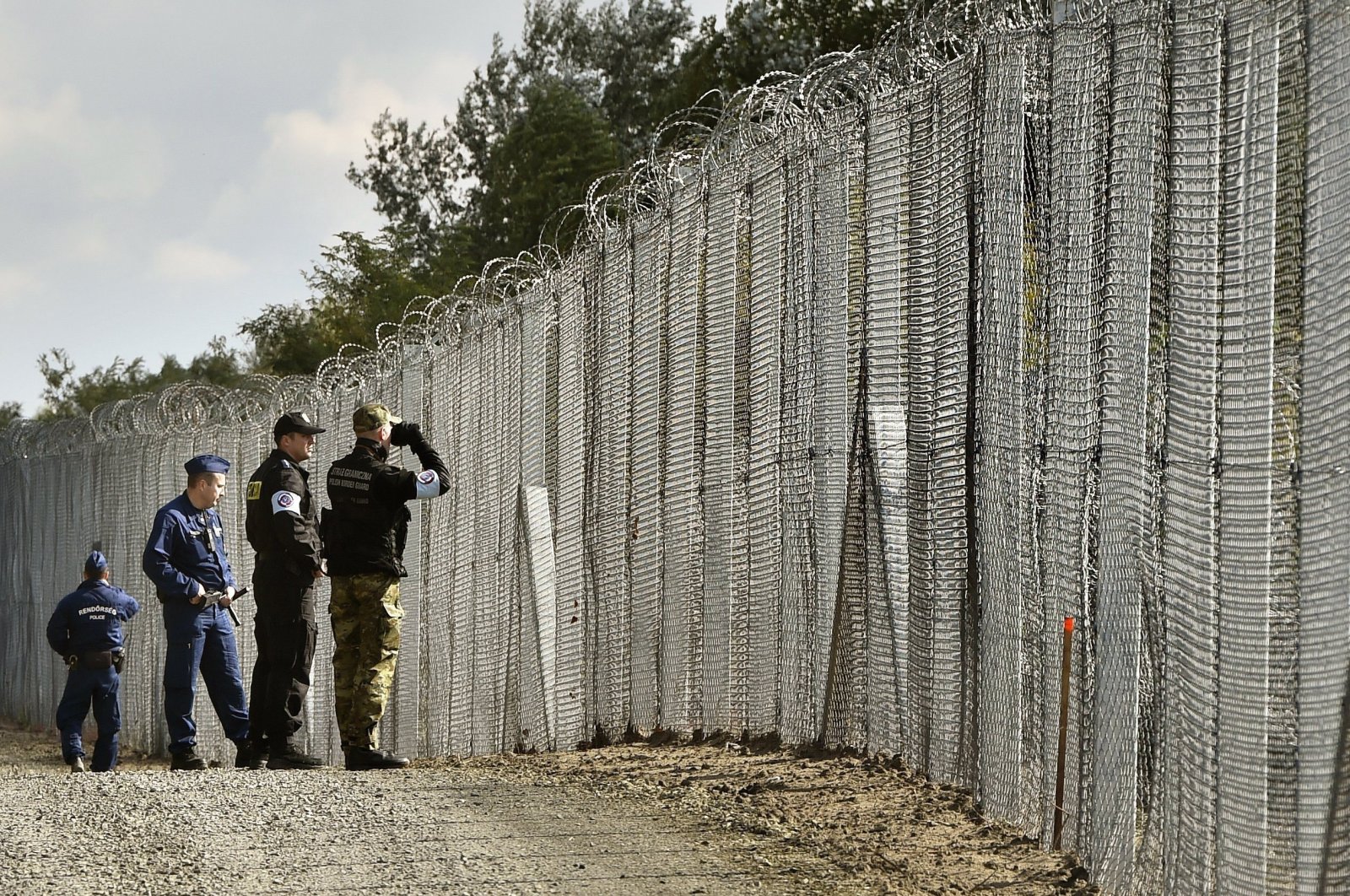 A police officer (2nd R) and border guard (R) of Poland patrol with Hungarian policemen along the temporary border fence on the Hungarian-Serbian border near Roszke, southeast of Budapest, Hungary, Oct.13, 2016. (AP Photo)