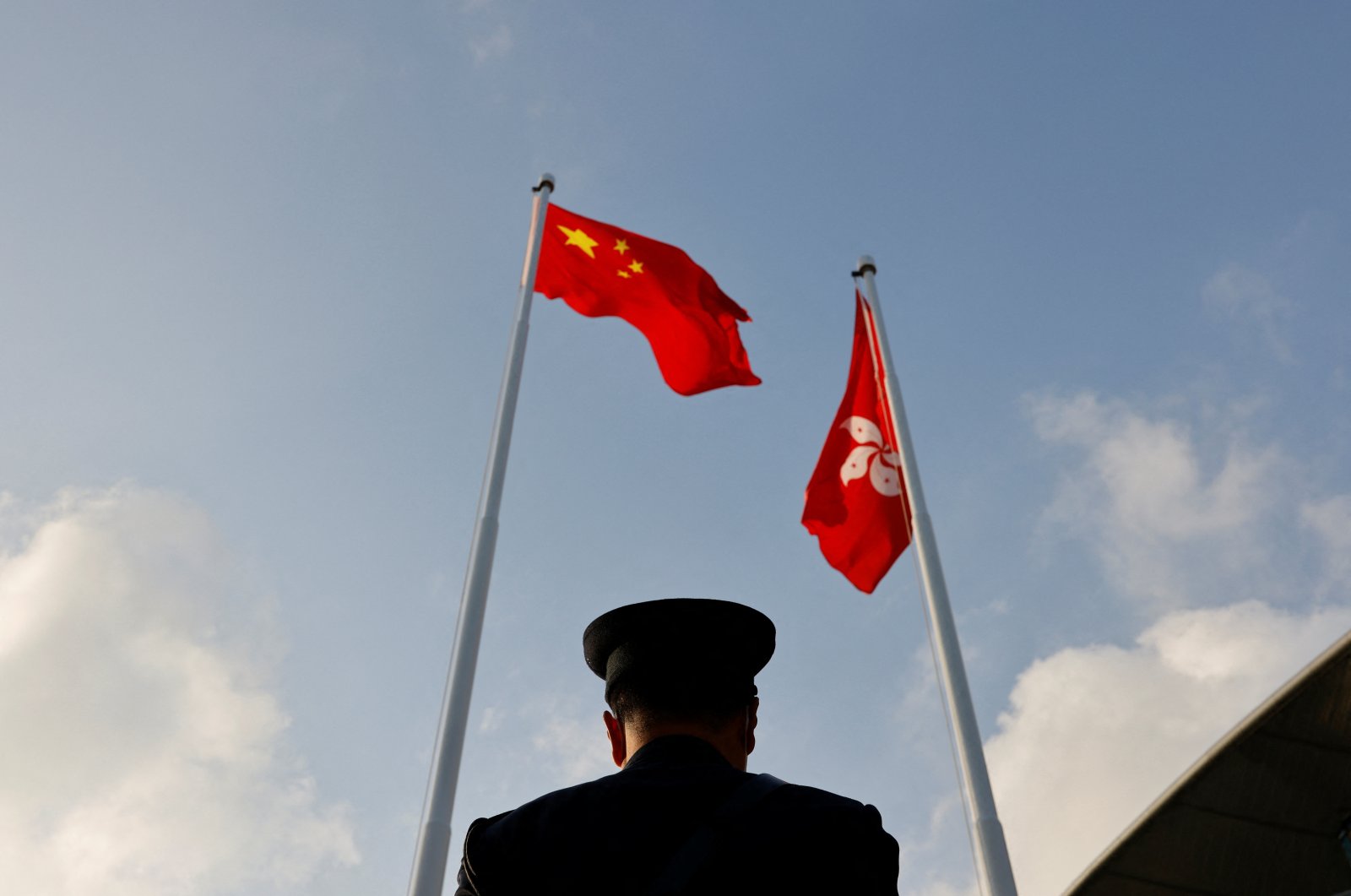 A police officer stands guard below China and Hong Kong flags during a flag raising ceremony, a week ahead of the Legislative Council election in Hong Kong, Dec. 12, 2021. (Reuters Photo)