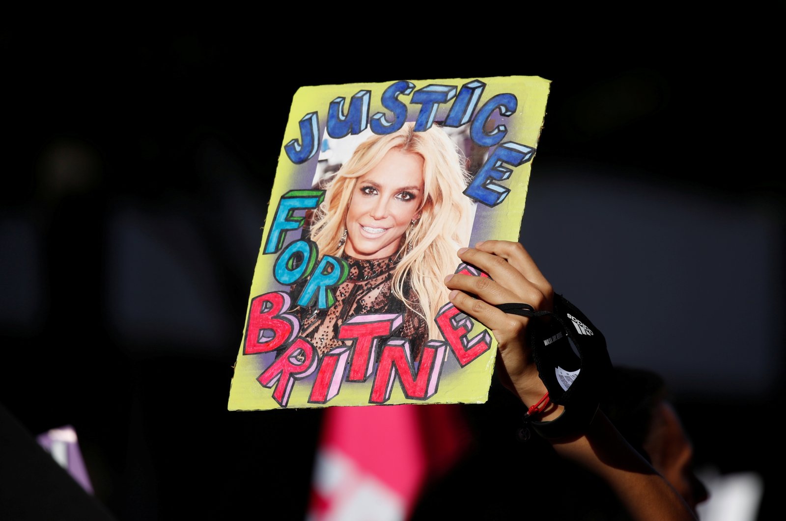 A supporter of singer Britney Spears holds up a picture of the pop star with the words "Justice for Britney" during celebrations of the termination of her conservatorship, outside the Stanley Mosk Courthouse in Los Angeles, California, U.S. Nov. 12, 2021. (REUTERS)