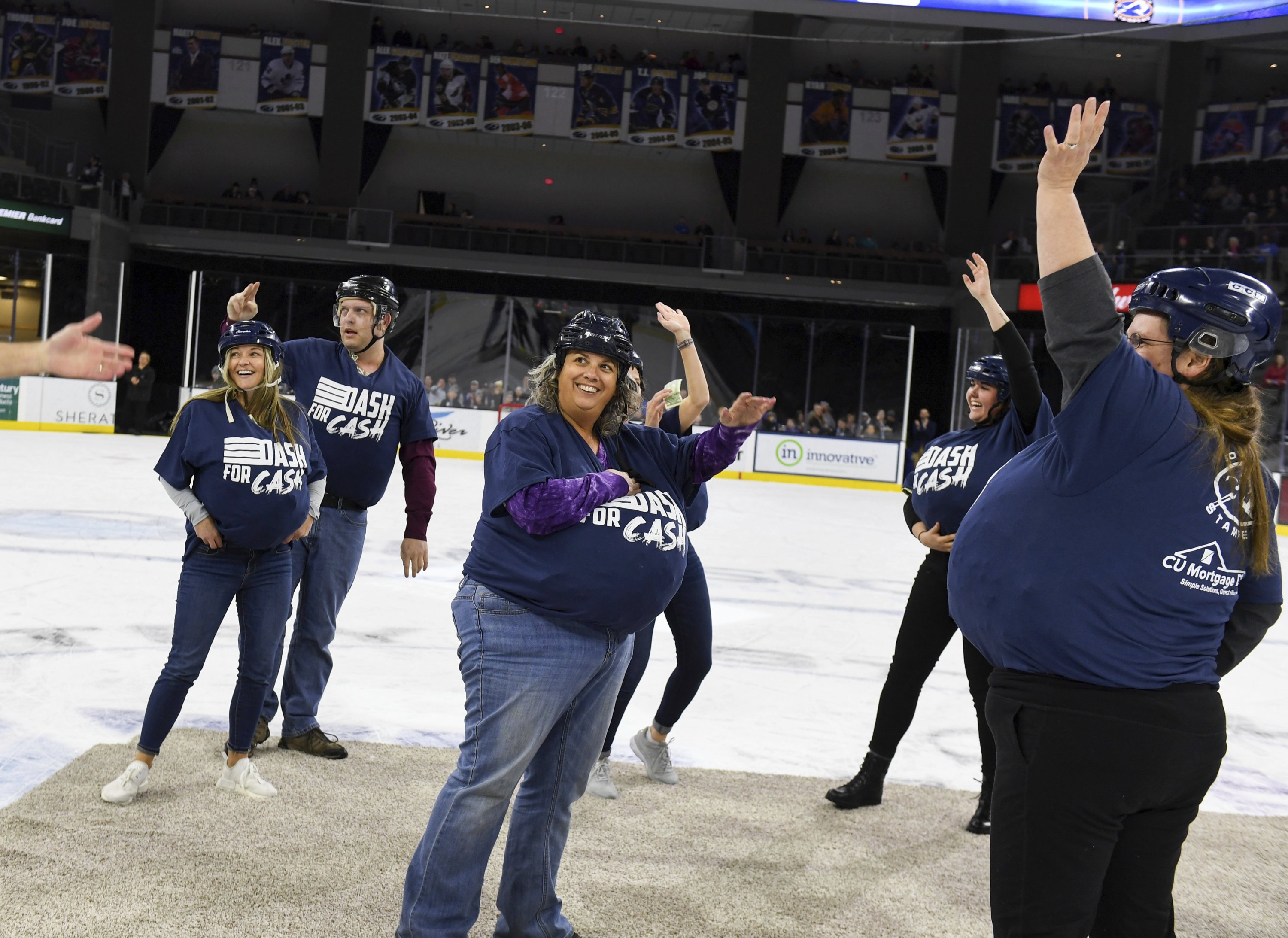 Local teachers wave to the crowd while holding piles of money in their shirts in the first-ever Dash For Cash between periods at the Sioux Falls Stampede game, South Dakota, U.S., Dec. 11, 2021. (AP Photo)