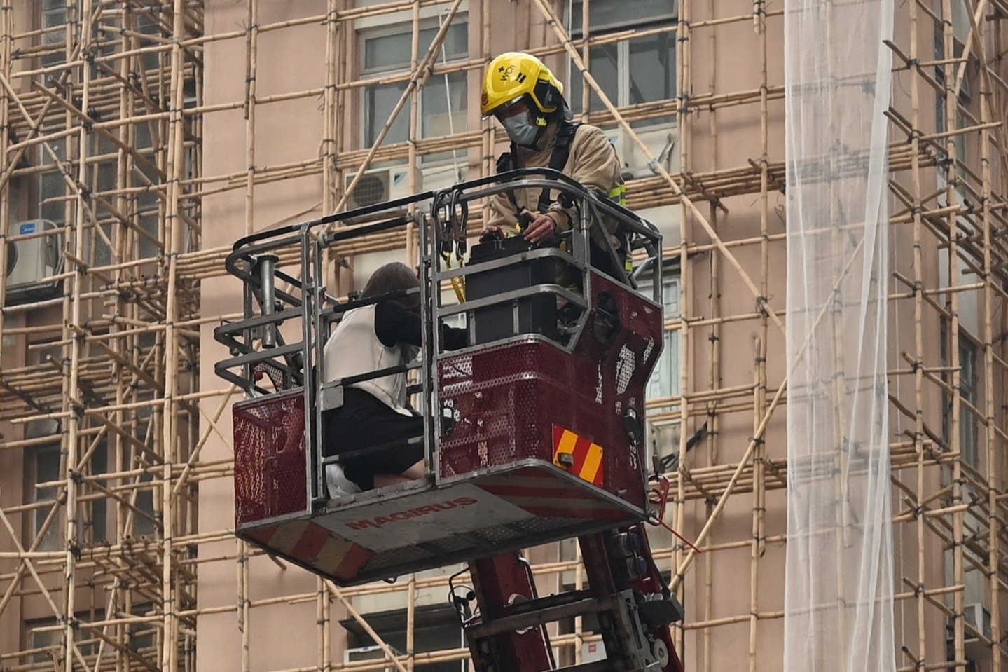 A fireman lowers the crane with a rescued person from Hong Kong's World Trade Center high-rise building, which suffered an electrical fire trapping hundreds on the rooftop, in the city's Causeway Bay district, Dec. 15, 2021. (AFP Photo)