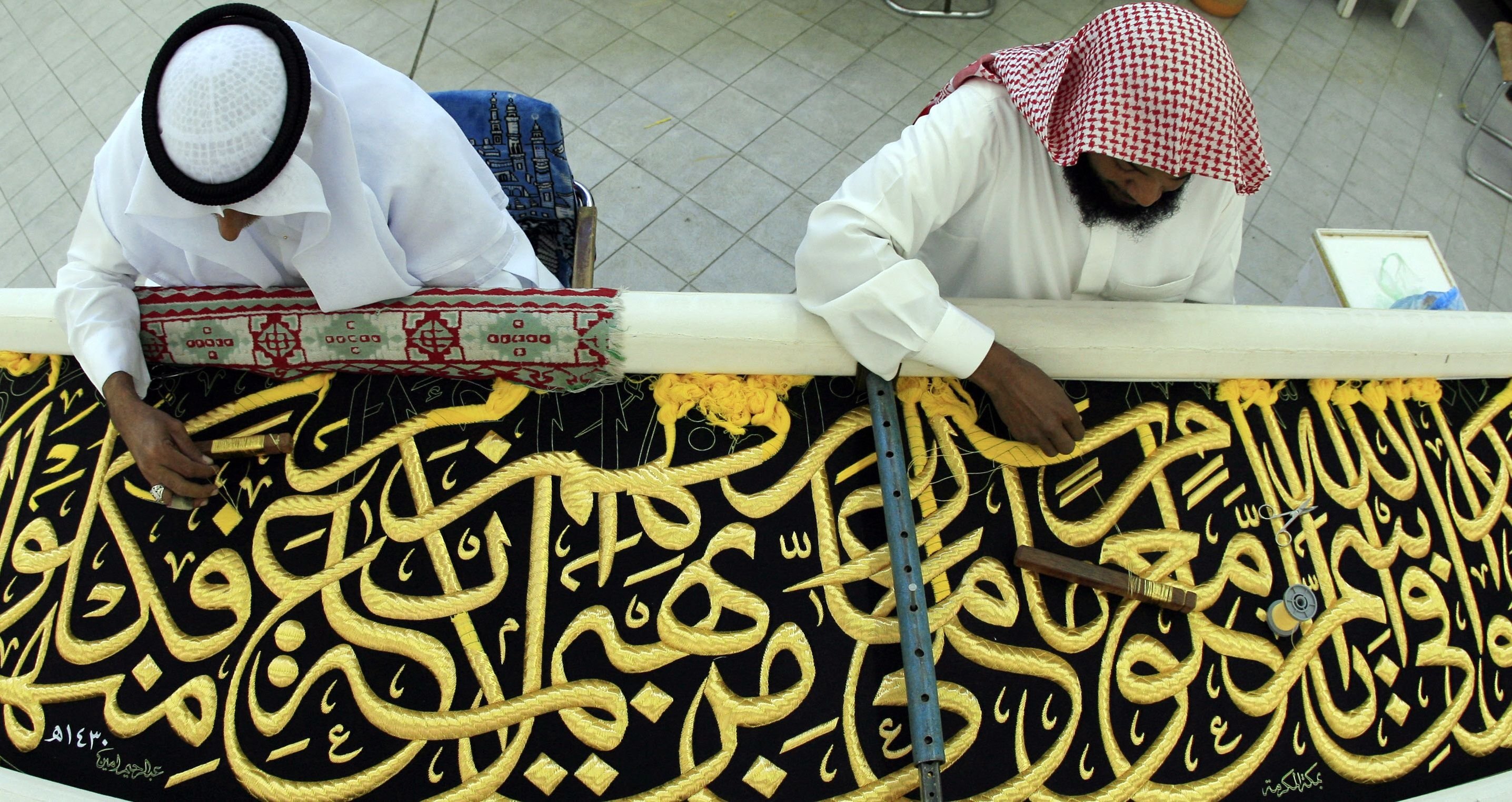 Workers sew Islamic Arabic calligraphy in gold thread on a drape to cover the Kaaba at the Kiswa factory in the holy city of Mecca, Saudi Arabia, Nov. 29, 2008. (AFP)