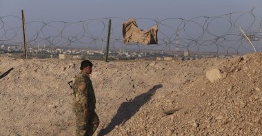 A YPG terrorist stands at the Syria-Turkey border in Tal Abyad town, Syria, Monday, Oct. 7, 2019. (AP File Photo)