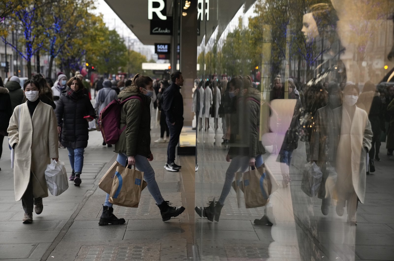A woman&#039;s reflection is seen as she walks into a shop on Oxford Street in London, Britain, Nov. 29, 2021. (AP Photo)