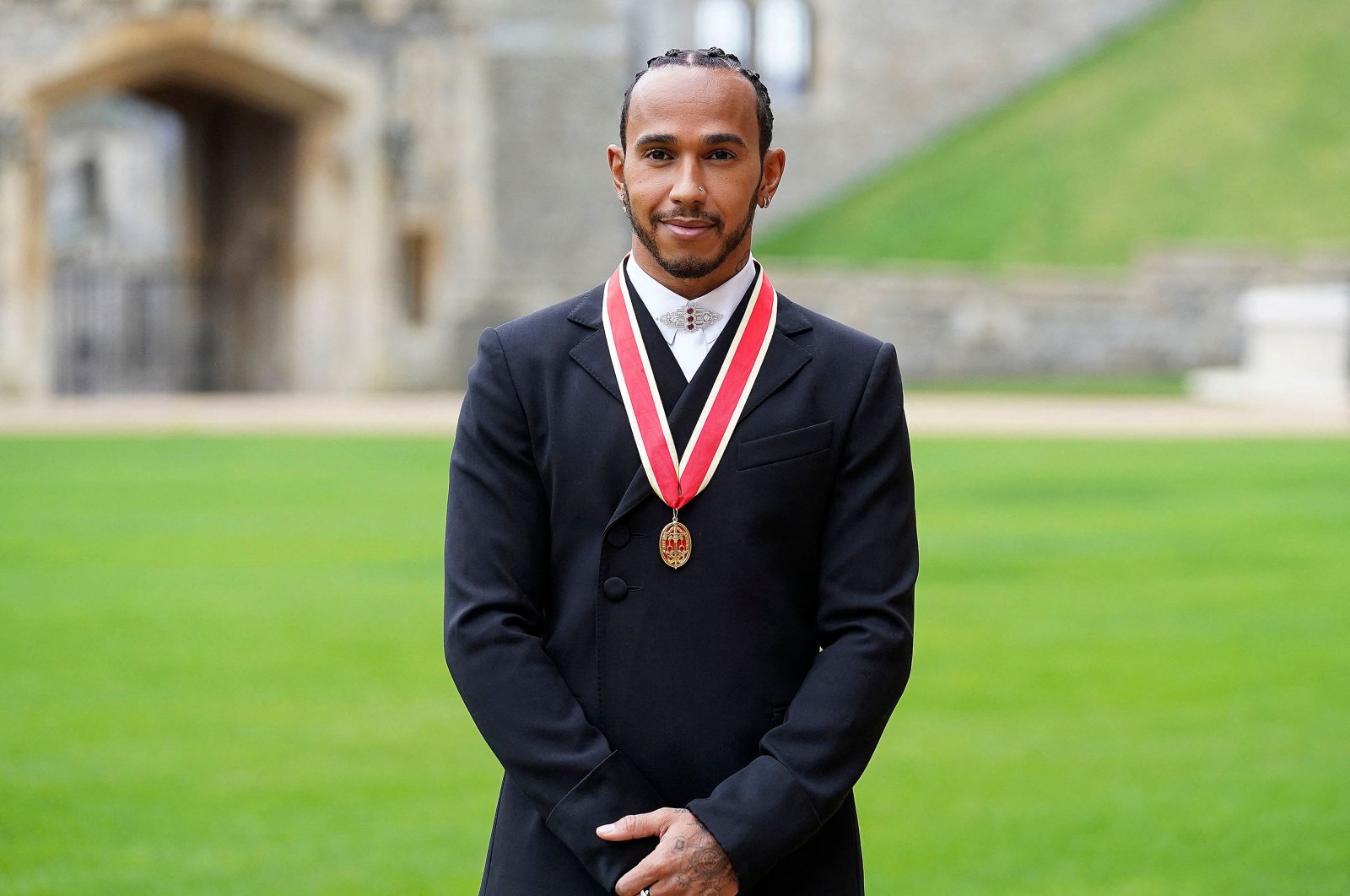 Mercedes&#039; British F1 driver Lewis Hamilton poses with his medal after being appointed as a Knight Bachelor (Knighthood) for services to motorsports, by Britain&#039;s Prince Charles, Prince of Wales, during an investiture ceremony at Windsor Castle in Windsor, west of London, Dec. 15, 2021. (AFP Photo)