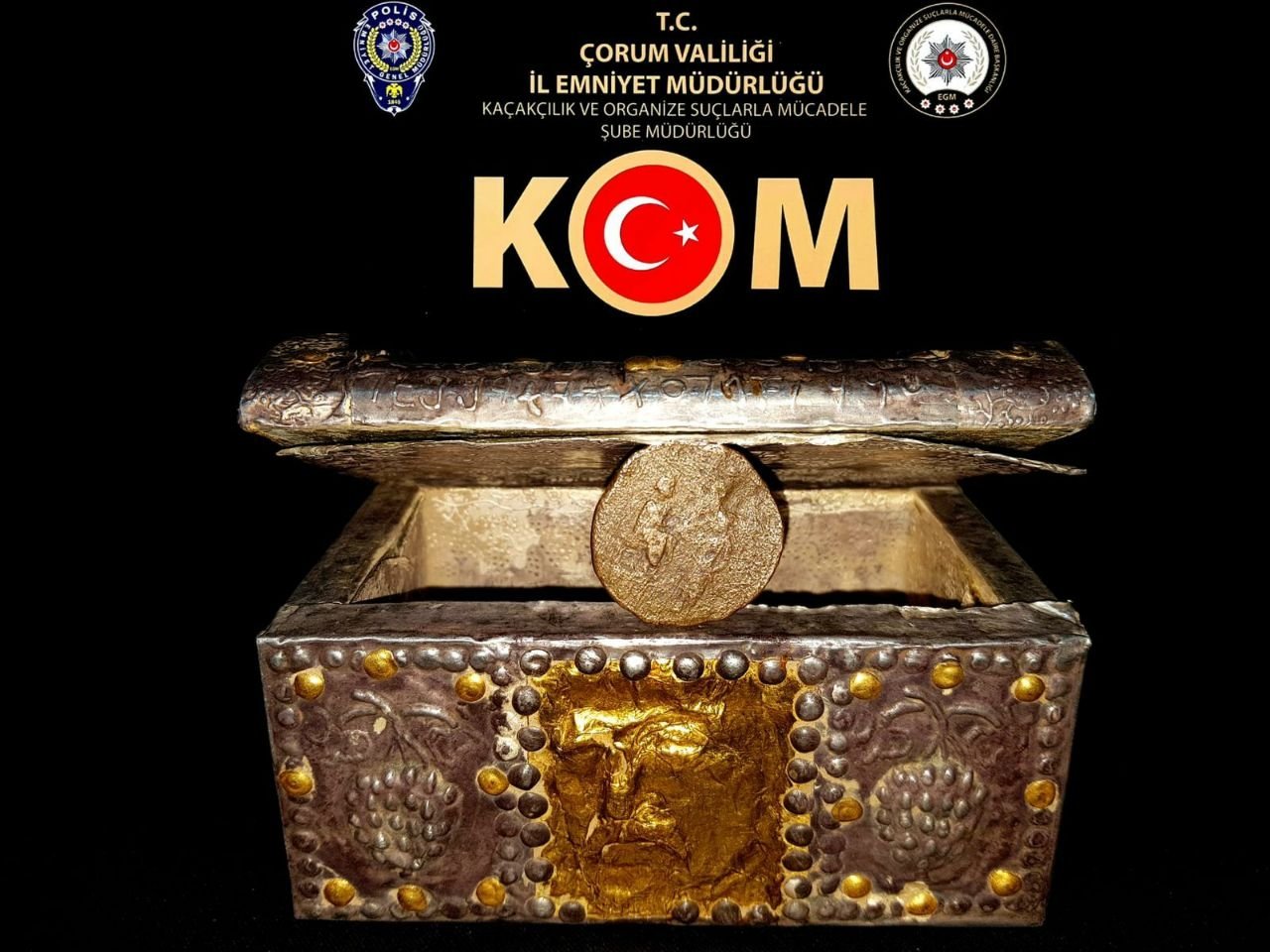 The historical chest and gold coin are on display in front of a logo of the authorities, Çorum, central Turkey, Dec. 14, 2021. (AA Photo)
