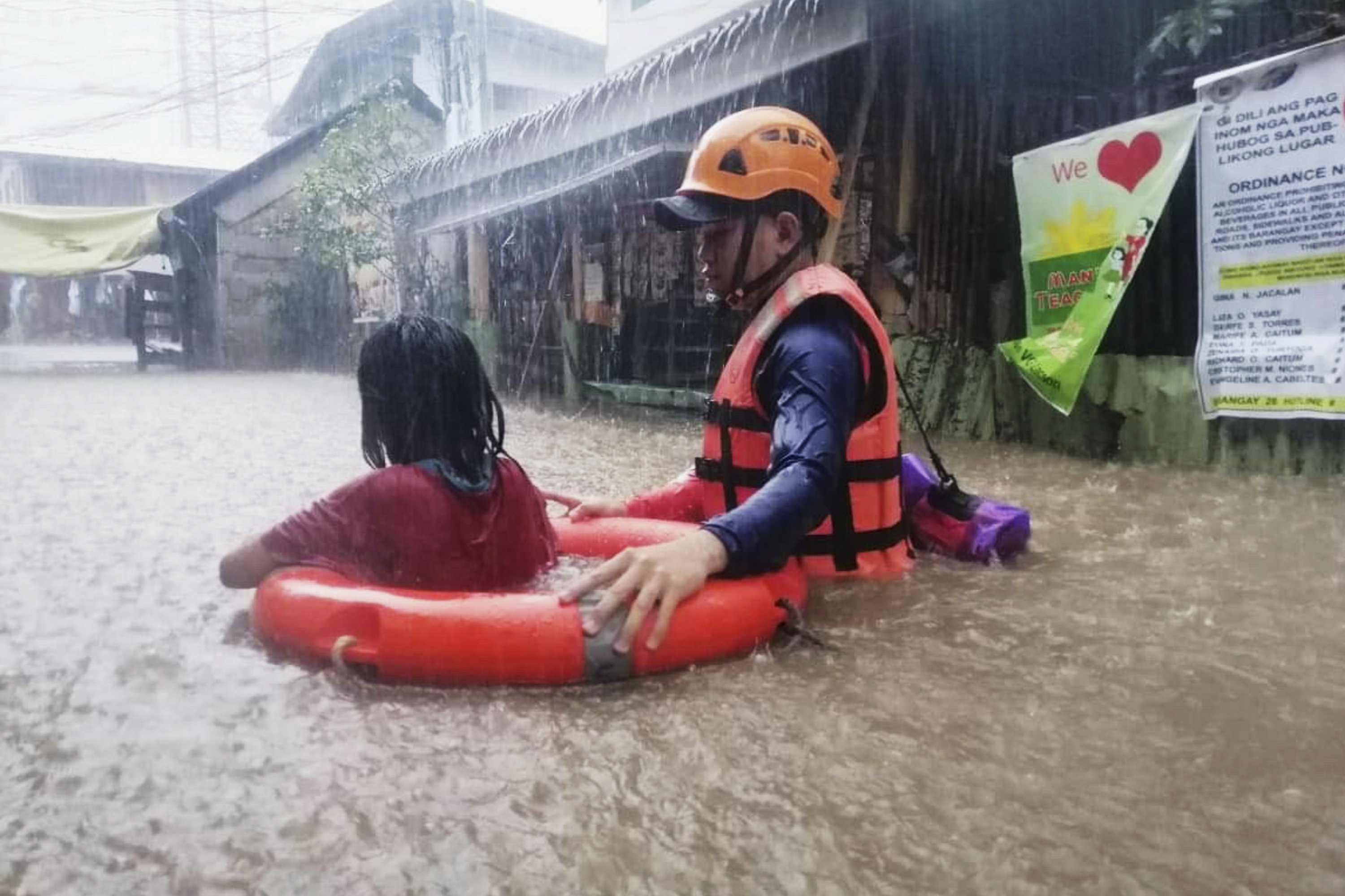 A rescuer assists a girl as they wade through flooding caused by Typhoon Rai in Cagayan de Oro City, southern Philippines, Dec. 16, 2021. (Philippine Coast Guard handout photo via AP)