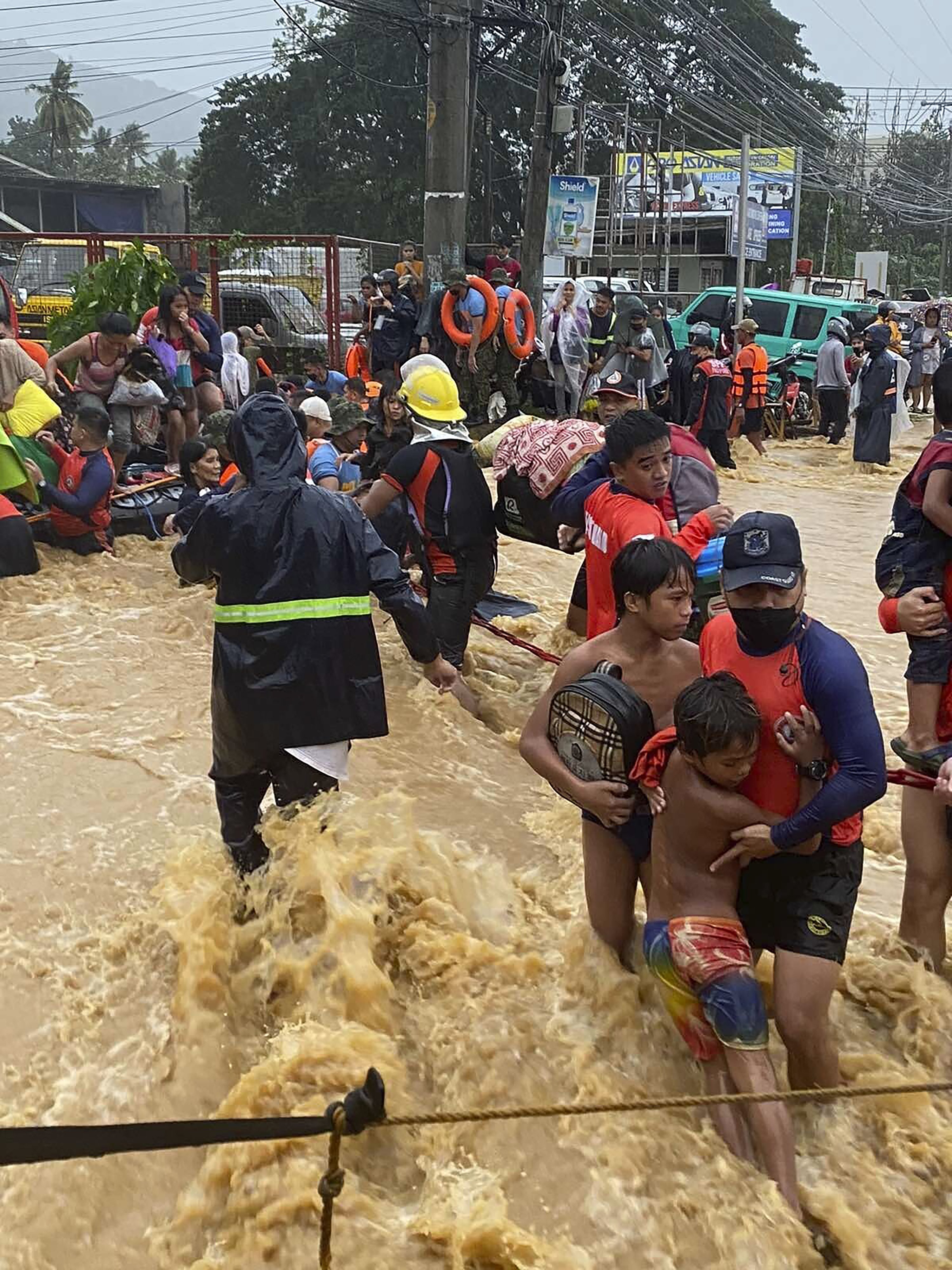 Rescuers assist residents over floodwaters caused by Typhoon Rai as they are evacuated to higher ground in Cagayan de Oro City, southern Philippines, Dec. 16, 2021. (Philippine Coast Guard handout photo via AP)