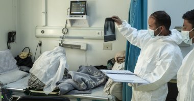 Staff of the Afghan-Japan Hospital look at a chest x-ray in the COVID-19 emergency ward section next to a patient in Kabul, Afghanistan, Dec. 9, 2021. (AP Photo)