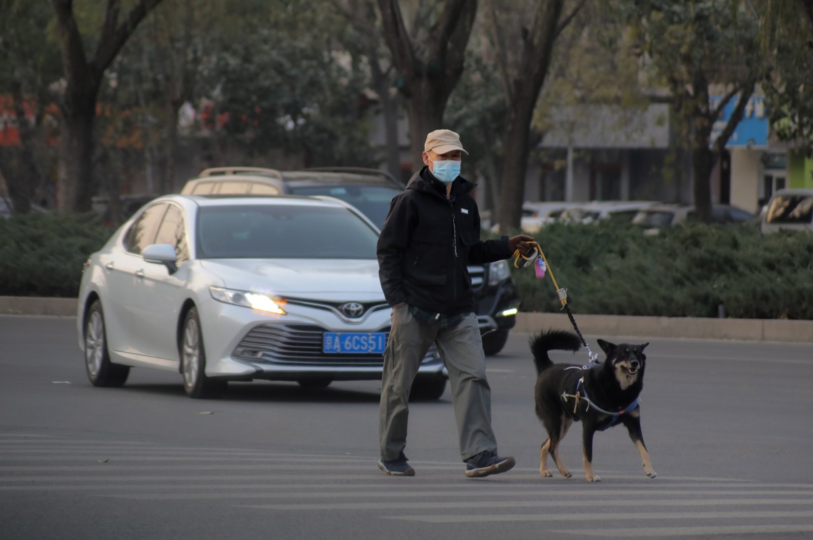A man wearing protective face mask walks with a pet dog in the street during the coronavirus pandemic in Beijing, China, Nov. 16, 2021. (EPA Photo) 