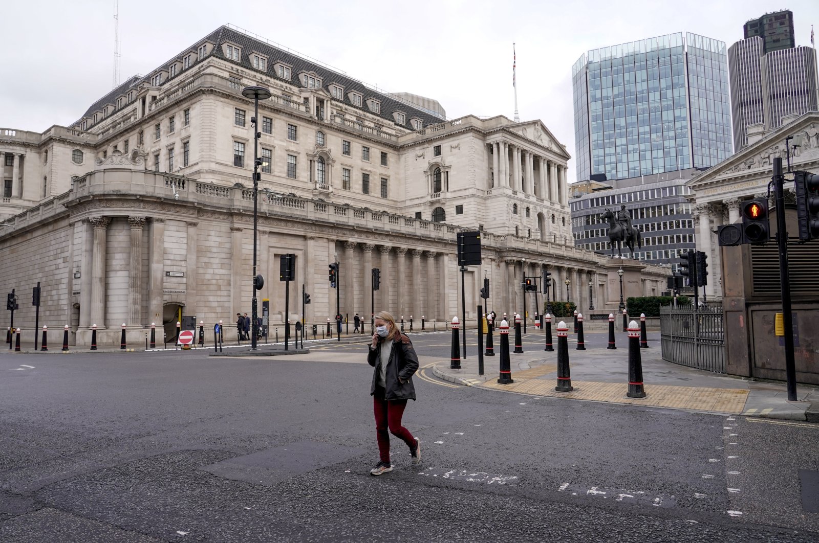 A woman wears a face mask while walking crossing a road outside the Bank of England in London, U.K., Dec. 13, 2021. (AP Photo)