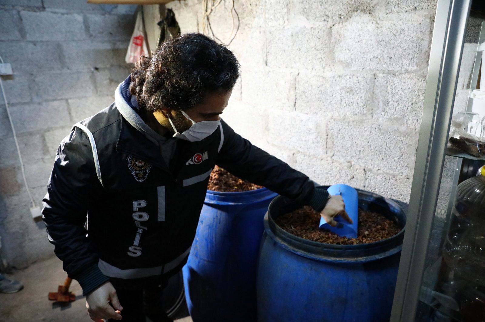A police officer checks materials used in bootleg liquor production seized in an operation in Adana, southern Turkey, Dec. 16, 2021. (PHOTO BY ZİYA RAMOĞLU)