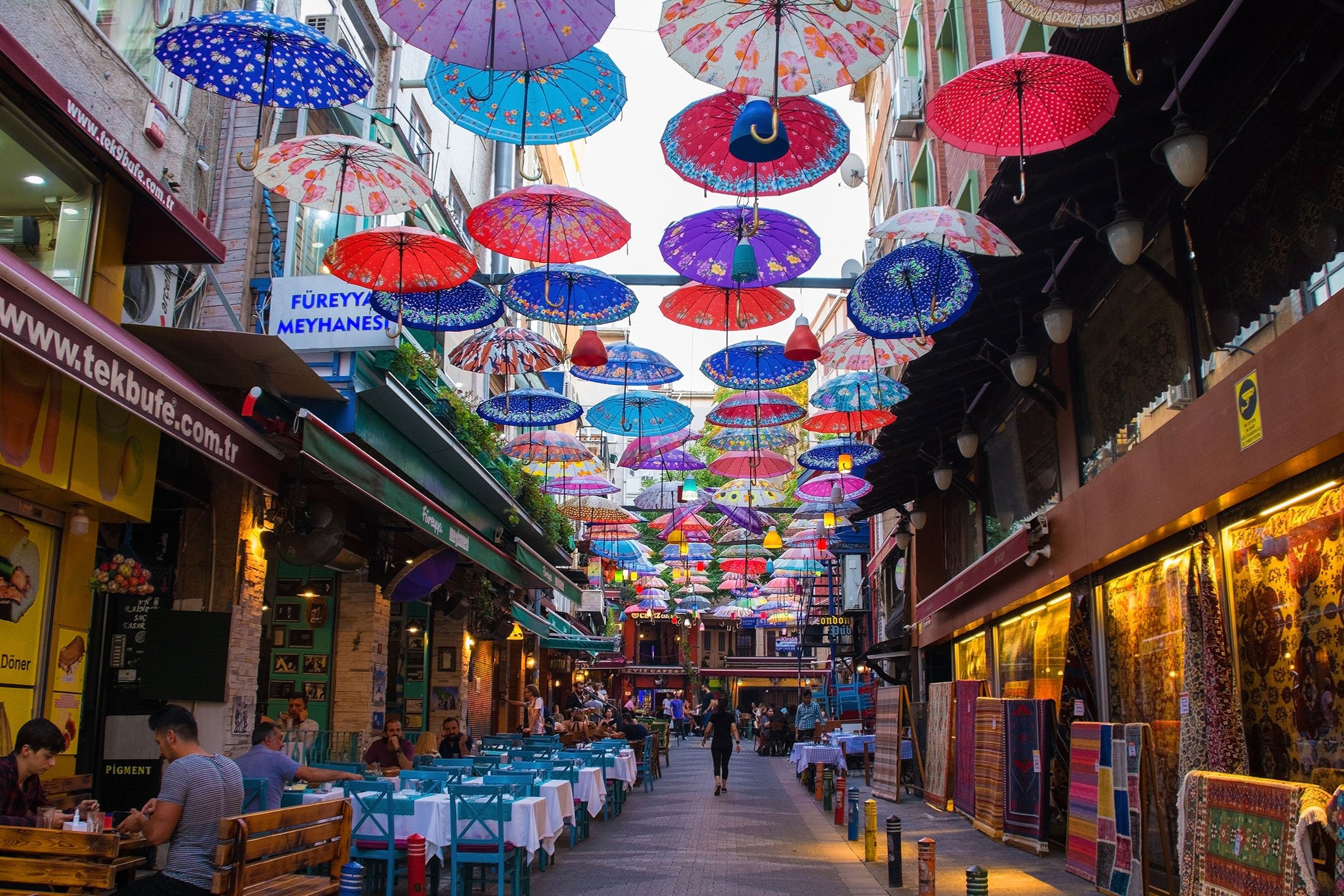 Colorful umbrellas hang from the sky covering a street of bars, restaurants and shops in Kadıköy, Istanbul. (Shutterstock Photo) 
