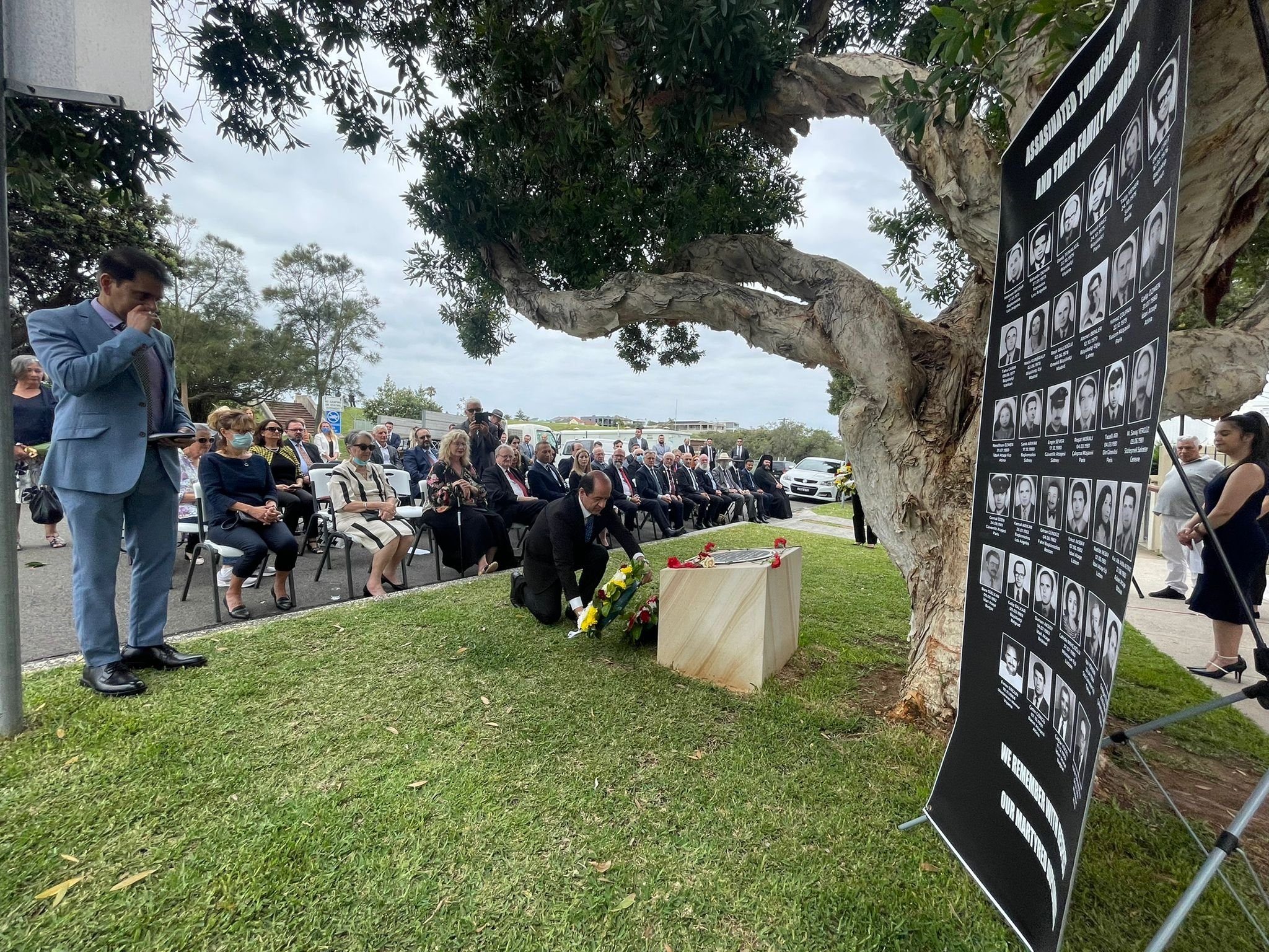 A panel displaying some of the Turkish diplomats murdered by Armenian terrorists (L), as people pay their respects to the victims at a ceremony honoring the dead, Sydney, Australia, Dec. 17, 2021. (AA Photo)