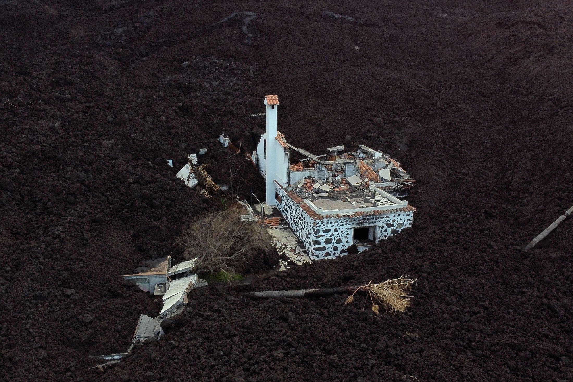 Foto udara ini menunjukkan rumah yang hancur tertutup lava setelah letusan gunung berapi Cumbre Vieja, di La Laguna, di Pulau Canary La Palma, Spanyol, 16 Desember 2021. (AFP Photo)
