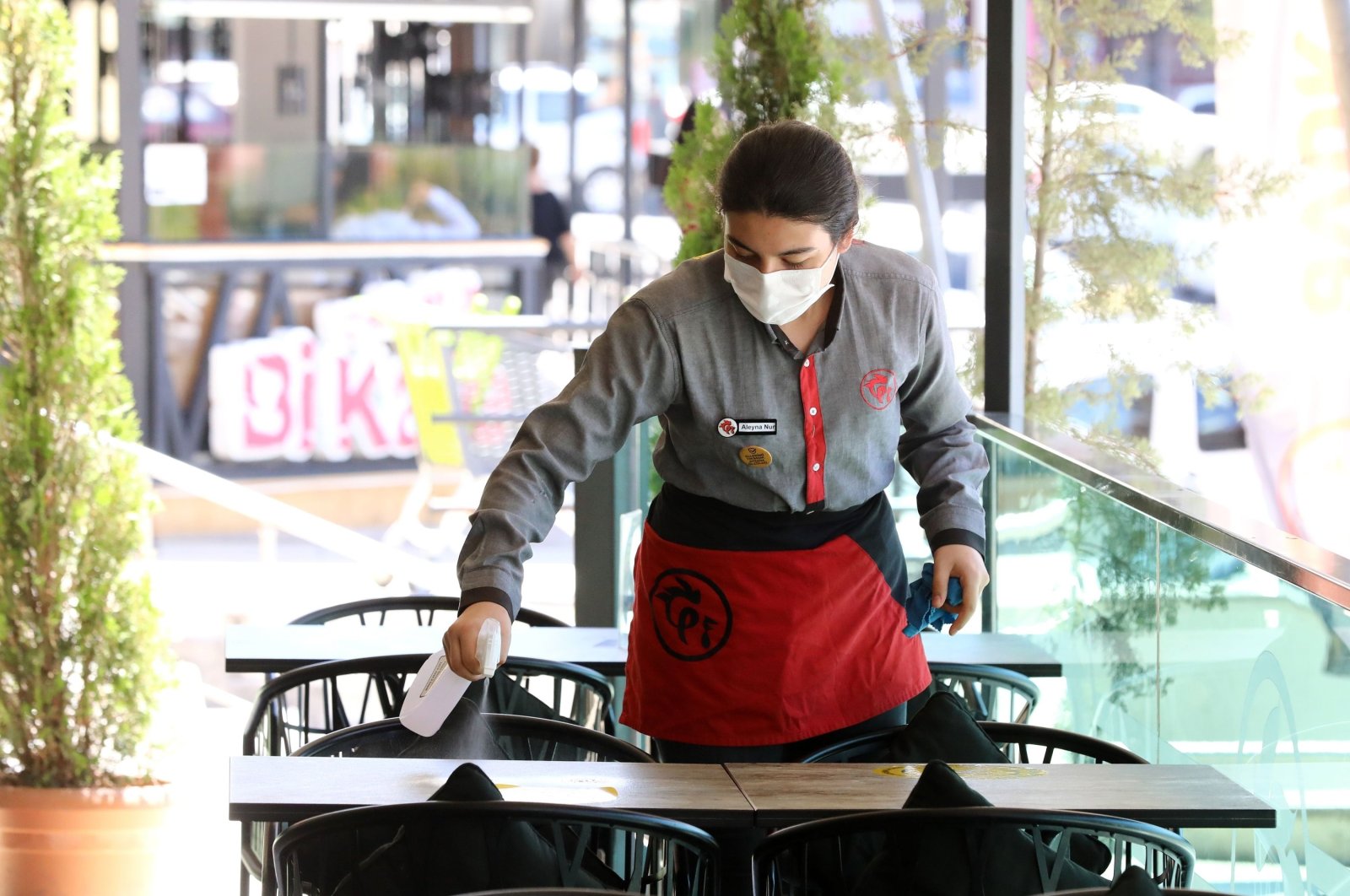 A waiter wearing a protective face mask disinfects a table at a restaurant in Ankara, Turkey, Aug. 6, 2020. (AFP Photo)