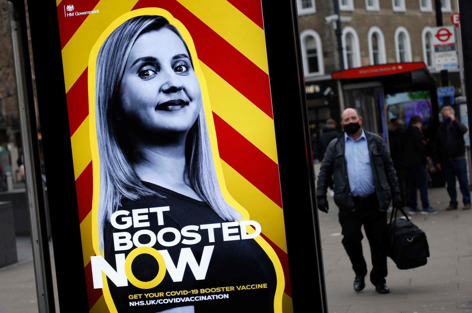 Pedestrians walk past a government advertisement promoting the NHS&#039; COVID-19 vaccine booster program at a bus stop in London, U.K., Dec. 17, 2021. (AFP Photo)