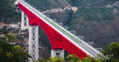 An electric multiple unit (EMU) train of the China-Laos Railway crosses a major bridge over the Yuanjiang River in southwestern China&#039;s Yunnan Province, Friday, Dec. 3, 2021. (Xinhua News Agency via AP)