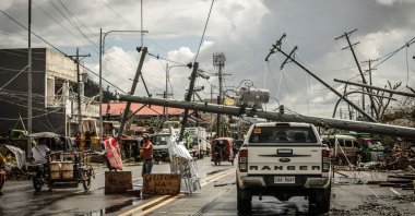 Fallen electric poles block a road while a sign asking for food (L) is displayed along a road in Surigao City, Surigao del norte province, Philippines, Dec. 19, 2021. (AFP Photo)
