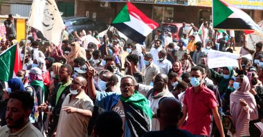 Sudanese demonstrators carry national flags and banners as they rally against the military chief who launched an Oct. 25 coup followed by a bloody crackdown, Khartoum, Sudan, Dec. 19, 2021. (AFP Photo)