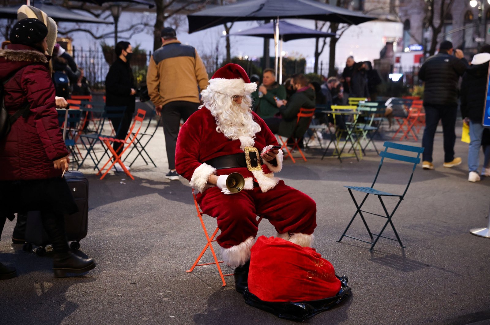 A person dresses as Santa Claus checks his cellphone as he sits outside of Macy&#039;s Herald Square as the omicron variant continues to spread, in Manhattan, New York City, U.S., Dec. 18, 2021. (Reuters Photo)