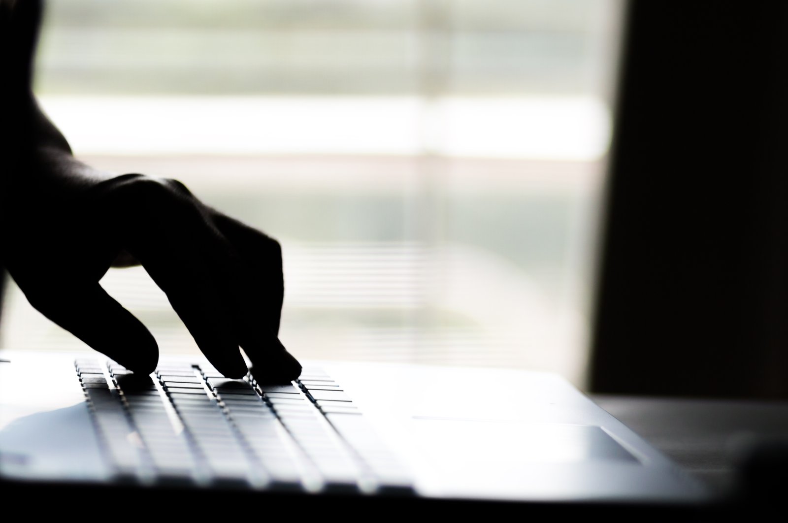 A hand reaching out through the screen of a laptop computer, signifying cybercrime. (Shutterstock)