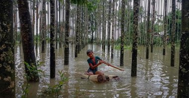 A child wades through a flooded area using a makeshift raft after monsoon floods and landslides have cut off more than 300,000 people in villages across southeast Bangladesh and killed at least 20 people including six Rohingya refugees, Cox's Bazar, Bangladesh, on July 30, 2021. (AFP Photo)