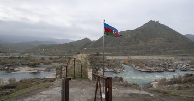 An Azerbaijani national flag flies next to the 13th century Khodaafarin Arch Bridge connecting the northern and southern banks of the Aras River located at the border of Azerbaijan and Iran, Jabrayil, Azerbaijan, Dec. 15, 2020. (Getty Images) 