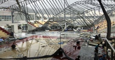 People stand inside a sport complex building whose roof collapsed after Super Typhoon Rai in Dapa town, Siargao Island, Philippines, Dec. 16, 2021. (AFP Photo)