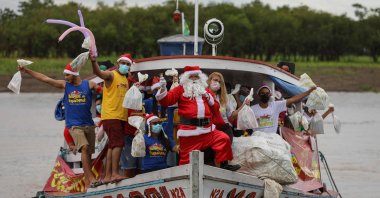 A member of the &quot;Amigos do Papai Noel&quot; (Friends of Santa Claus) group, wearing a Santa Claus costume, arrives to give presents to children, Careiro da Varzea, Brazil, Dec. 18, 2021. (AFP Photo)