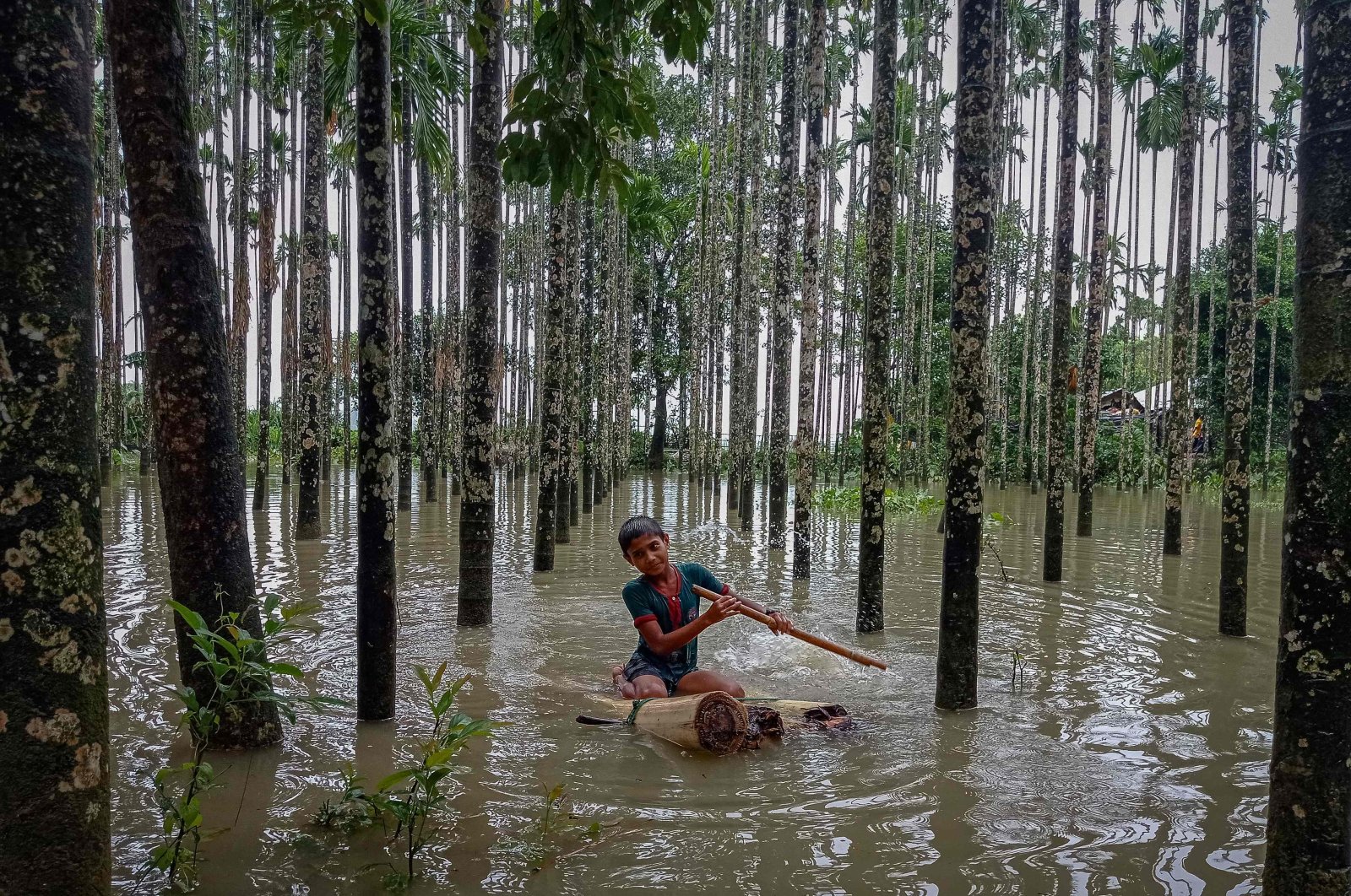 A child wades through a flooded area using a makeshift raft after monsoon floods and landslides have cut off more than 300,000 people in villages across southeast Bangladesh and killed at least 20 people including six Rohingya refugees, Cox&#039;s Bazar, Bangladesh, on July 30, 2021. (AFP Photo)