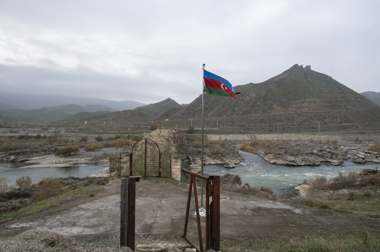 An Azerbaijani national flag flies next to the 13th century Khodaafarin Arch Bridge connecting the northern and southern banks of the Aras River located at the border of Azerbaijan and Iran, Jabrayil, Azerbaijan, Dec. 15, 2020. (Getty Images) 