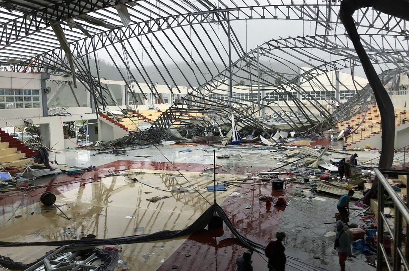 People stand inside a sport complex building whose roof collapsed after Super Typhoon Rai in Dapa town, Siargao Island, Philippines, Dec. 16, 2021. (AFP Photo)