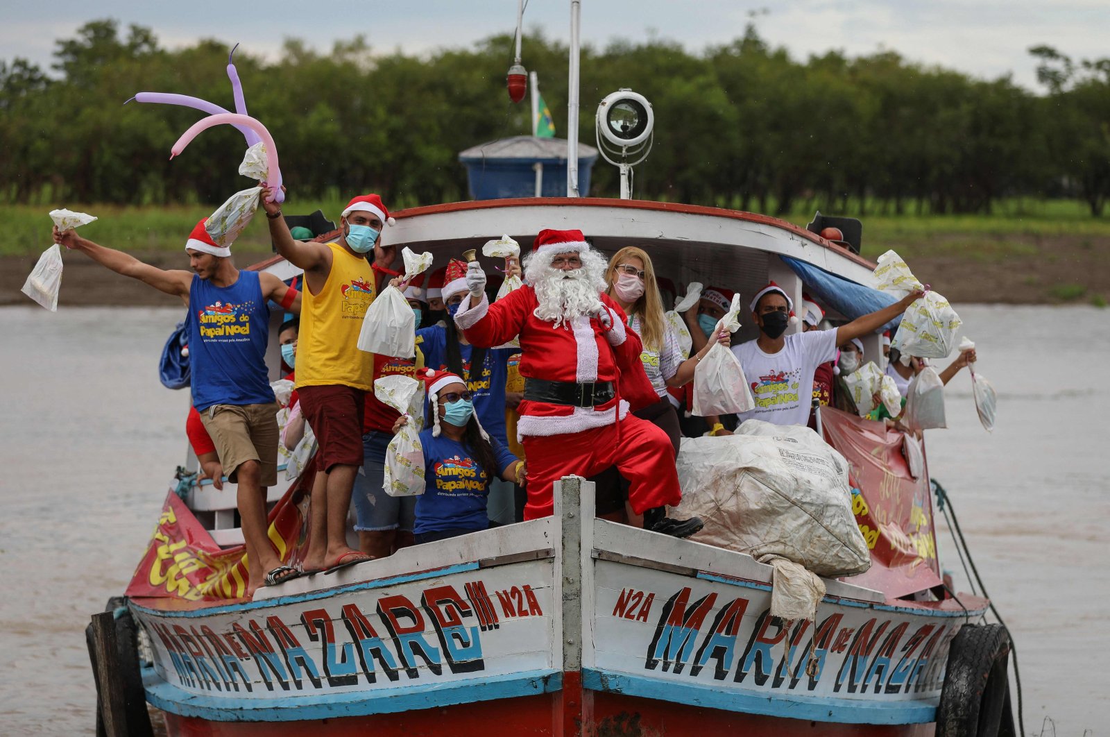 A member of the &quot;Amigos do Papai Noel&quot; (Friends of Santa Claus) group, wearing a Santa Claus costume, arrives to give presents to children, Careiro da Varzea, Brazil, Dec. 18, 2021. (AFP Photo)