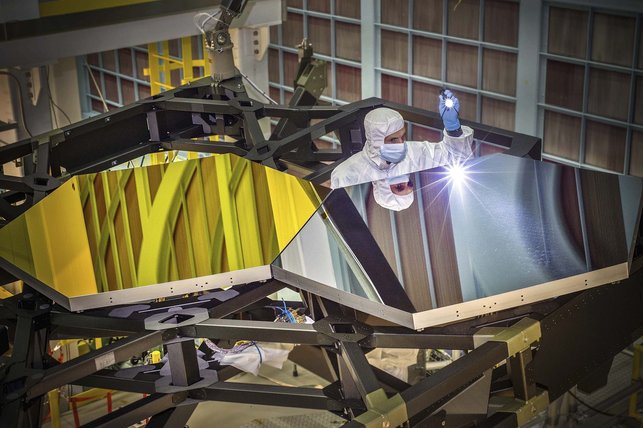 James Webb Space Telescope Optical Engineer Larkin Carey examines two test mirror segments on a prototype at the Goddard Space Flight Center's giant clean room in Greenbelt, Maryland, U.S., Sept. 29, 2014. (NASA via AP)