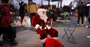 A person dressed as Santa Claus checks his cellphone as he sits outside of Macy's Herald Square as the omicron coronavirus variant continues to spread, in Manhattan, New York City, U.S., Dec. 18, 2021. (Reuters Photo)
