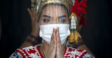 A Thai dancer wears a face mask and face shield during a performance to worship Lord Brahma, the Hindu God of creation, at the nearly empty tourist spot of Erawan Shrine in Bangkok, Thailand, Dec. 21, 2021. (EPA Photo)