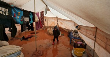 A child walks inside a flooded tent at a camp by the village of Killi, near Bab al-Hawa by the border with Turkey, in Syria's Idlib province, Dec. 20, 2021. (AFP Photo)