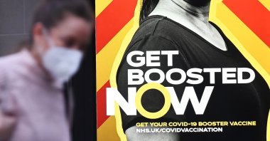 A shopper walks past a government COVID-19 booster campaign advertisement in London, Britain, Dec. 15, 2021. (EPA Photo)