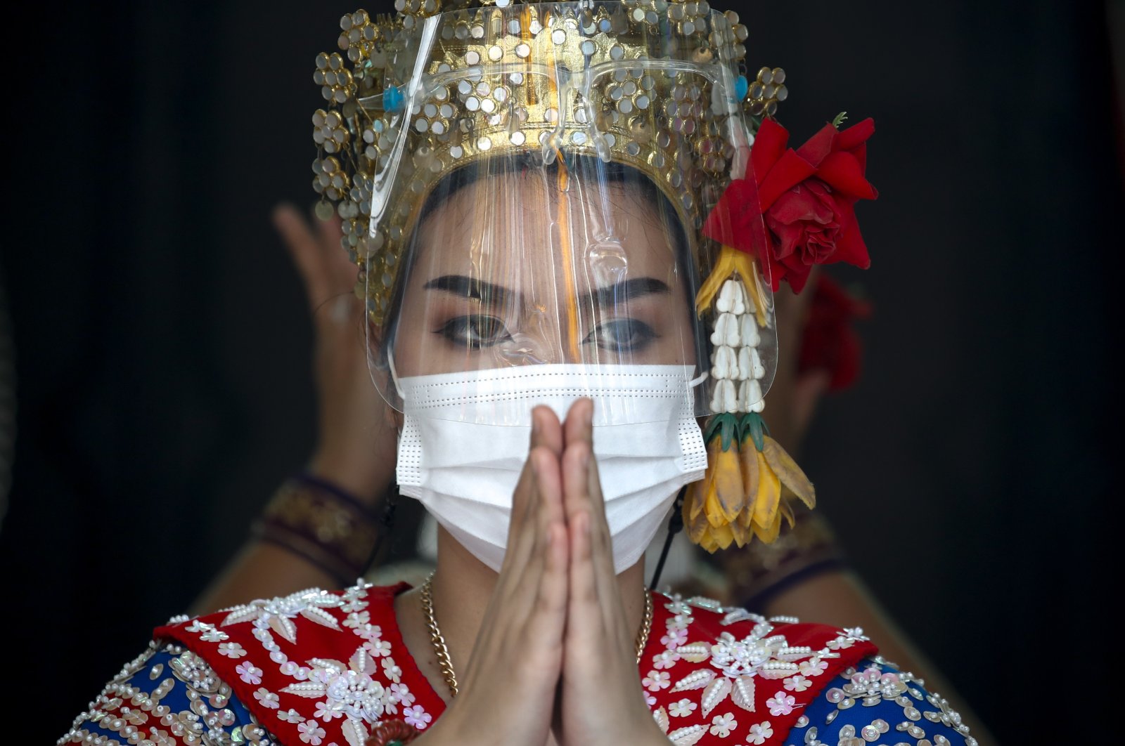 A Thai dancer wears a face mask and face shield during a performance to worship Lord Brahma, the Hindu God of creation, at the nearly empty tourist spot of Erawan Shrine in Bangkok, Thailand, Dec. 21, 2021. (EPA Photo)