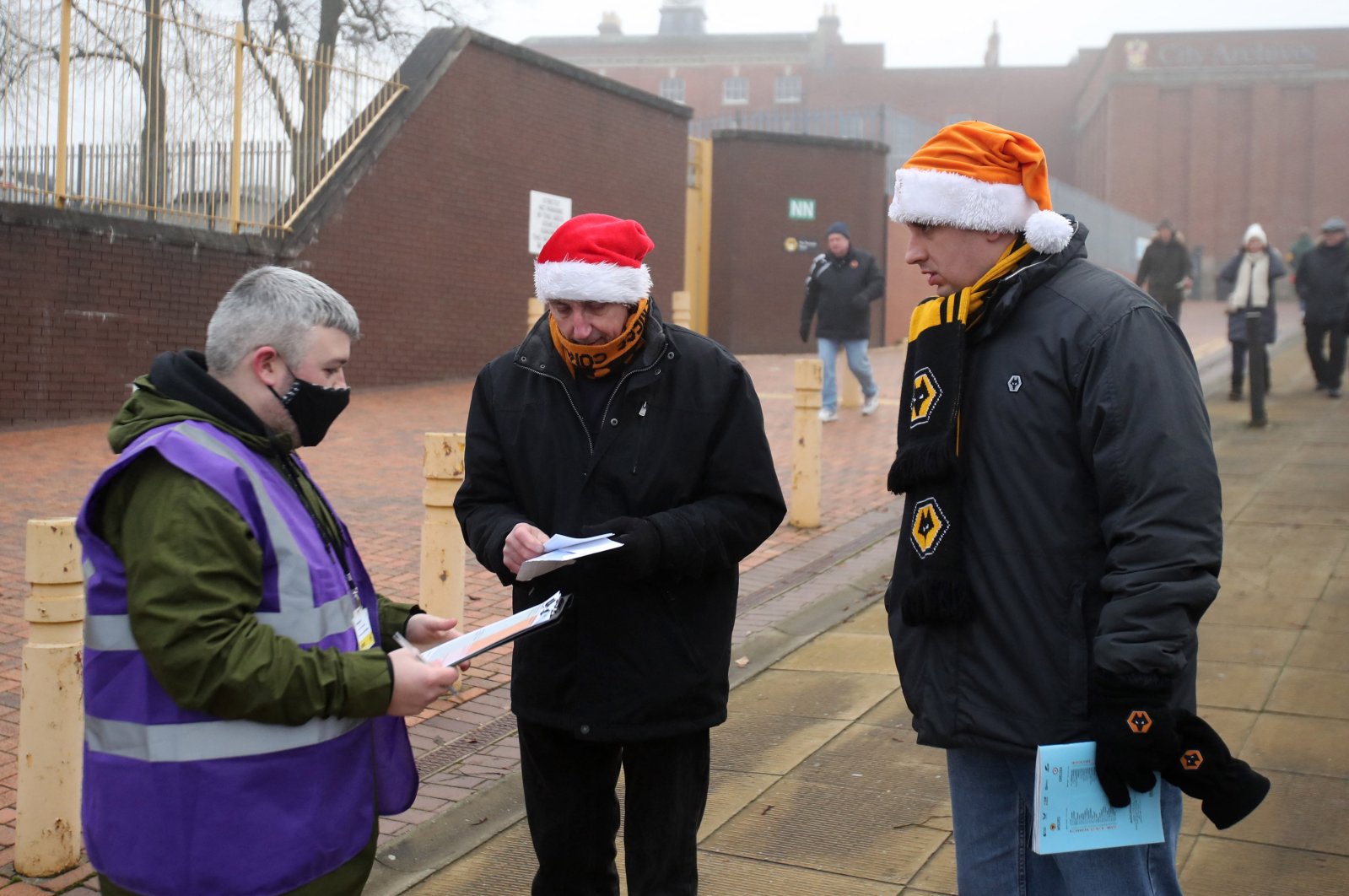 Fans get their COVID-19 passes checked outside the stadium before a Premier League match between Wolves and Chelsea, Wolverhampton, England, Dec. 19, 2021.